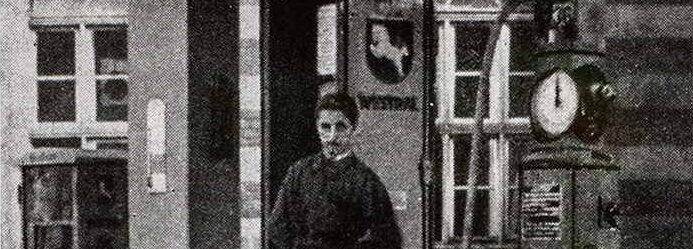 Schwarz-Weiß-Fotografie, Mann steht vor einer Westfalen Tankstelle