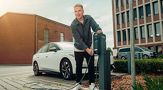 Mitarbeiter bedient E-Auto Ladesäule auf Firmenparkplatz