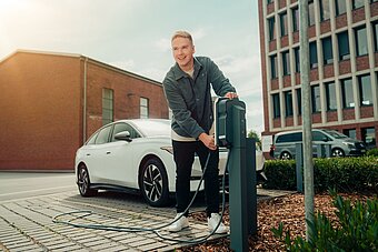 Mitarbeiter lädt seinen Firmenwagen an Ladestation auf Firmenparkplatz