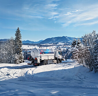 Weiß-blauer Westfalengas Lkw liefert Flüssiggas in schneebedeckter Bergregion aus