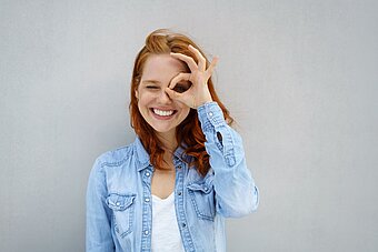 lachende frau schaut durch ihre finger