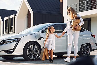 Mutter und Tochter zuhause vor E-Auto Dienstwagen und Wallbox