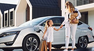 Mutter und Tochter Zuhause am E-Auto während Ladevorgang
