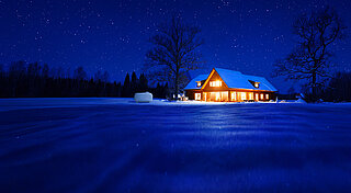 Beleuchtetes Haus auf dem Land im Schnell bei Nacht mit Flüssiggastank