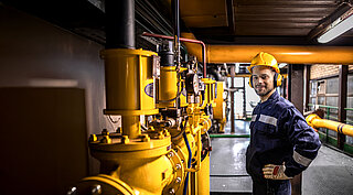 Mitarbeiter in Arbeitskleidung an einer Industrieanlage