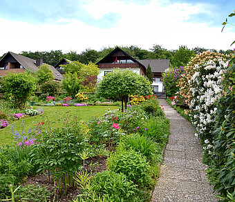 Haus mit großem Garten mit vielen Pflanzen, Blumen und Rasen