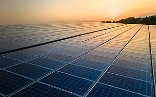 Blue photovoltaic solar panels mounted on building roof for producing clean ecological electricity at sunset. Production of renewable energy concept