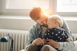 Vater und Sohne auf Couch vor Heizung