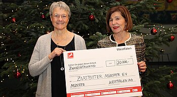Renate Fritsch-Albert von der Westfalen-Gruppe übergibt einen Scheck an Astrid-Maria Kreyerhoff vom Verein Zartbitter Münster