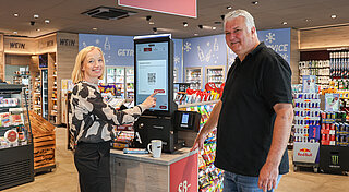 A woman and a man at a self check out terminal in a filling station