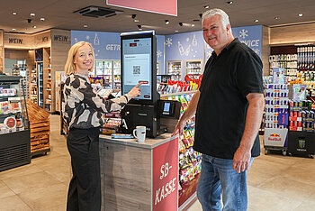 A woman and a man at a self-service checkout at a filling station