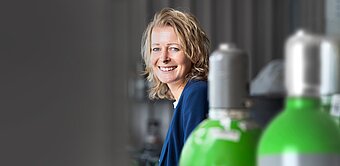 Lächelnde Frau steht bei Gasflaschen