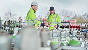 Gaseumrechner Westfalen AG. Mitarbeiter stehen inmitten von Gasflaschen
