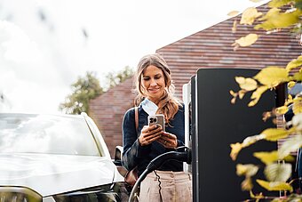 Frau lädt Firmenwagen zuhause an Wallbox