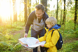 Vater und Sohne im Wald mit Landkarte