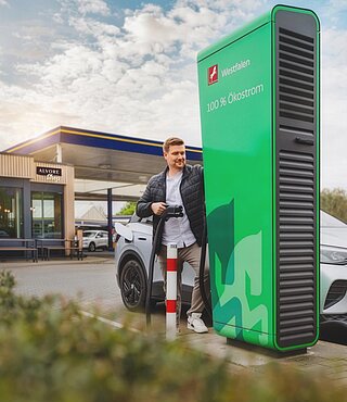 Mobilität und Tankstellen. Junge Frau steht vor Ihrem ladenden E-Auto