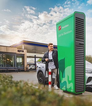 E-Auto unterwegs laden. Junge Frau steht vor Ihrem ladenden E-Auto